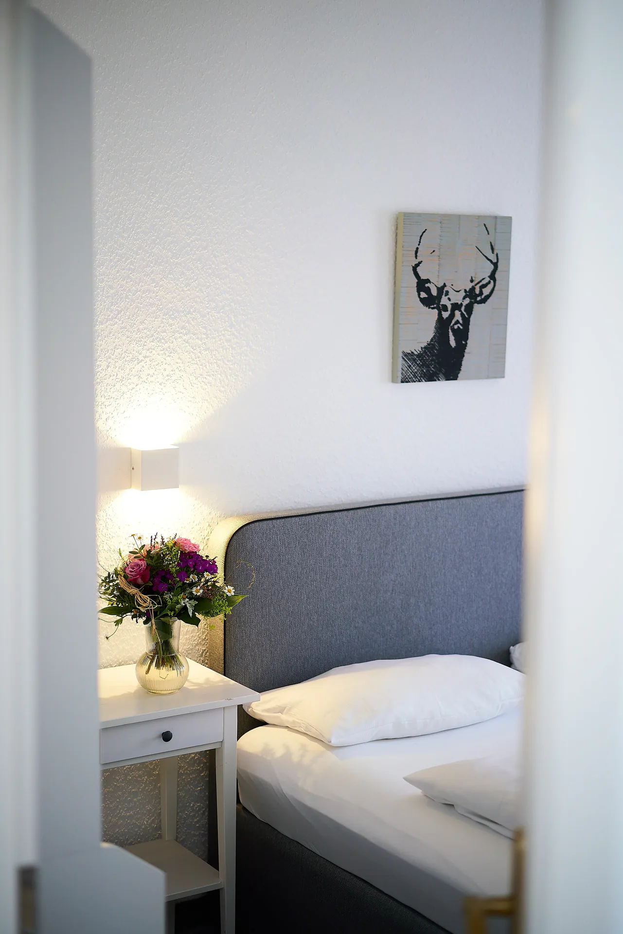 Standard-Doppelzimmer: Bett mit Nachttisch und Blumen